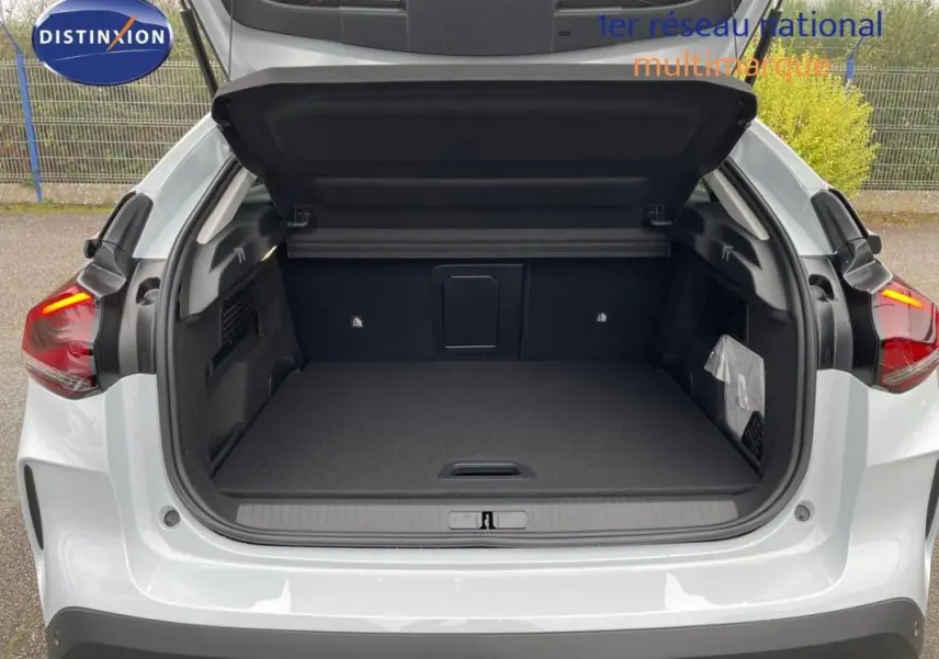 Coffre ouvert vu de l'arrière d'une Citroën C4 blanche 2024, montrant un espace de chargement spacieux et propre.