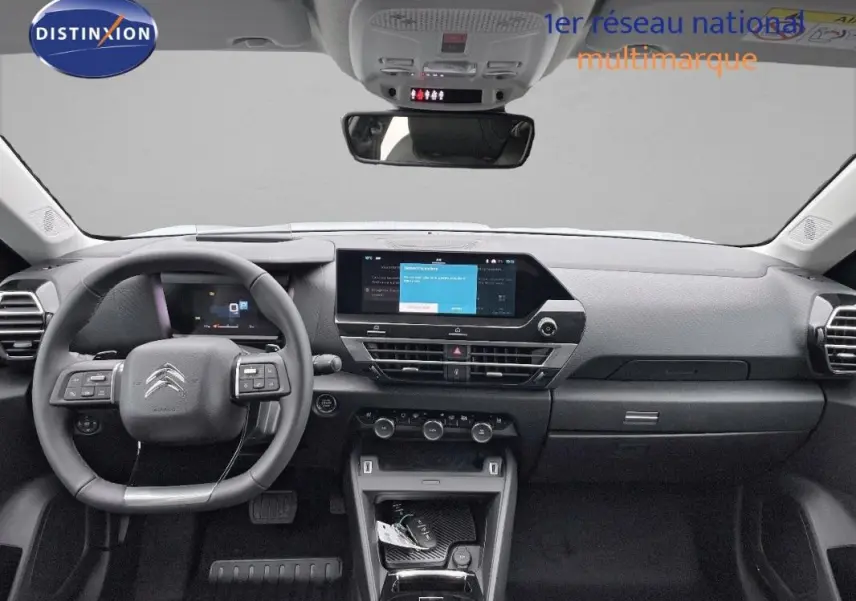 Vue frontale de l’habitacle du Citroën C4 blanc 2024, avec tableau de bord numérique et écran tactile central.