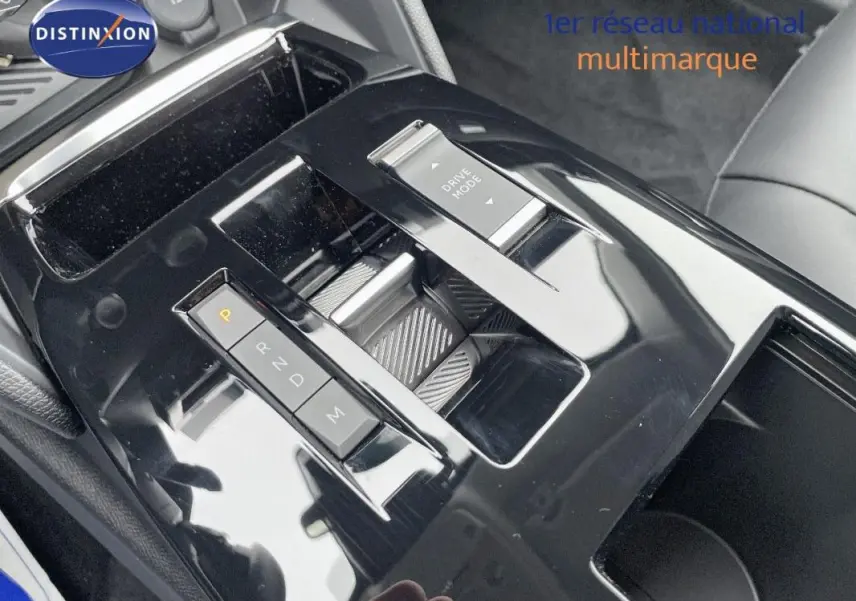 Gros plan sur la console centrale noire brillante de la Citroën C4 blanche 2024, avec sélecteur de boîte auto et bouton Drive Mode.