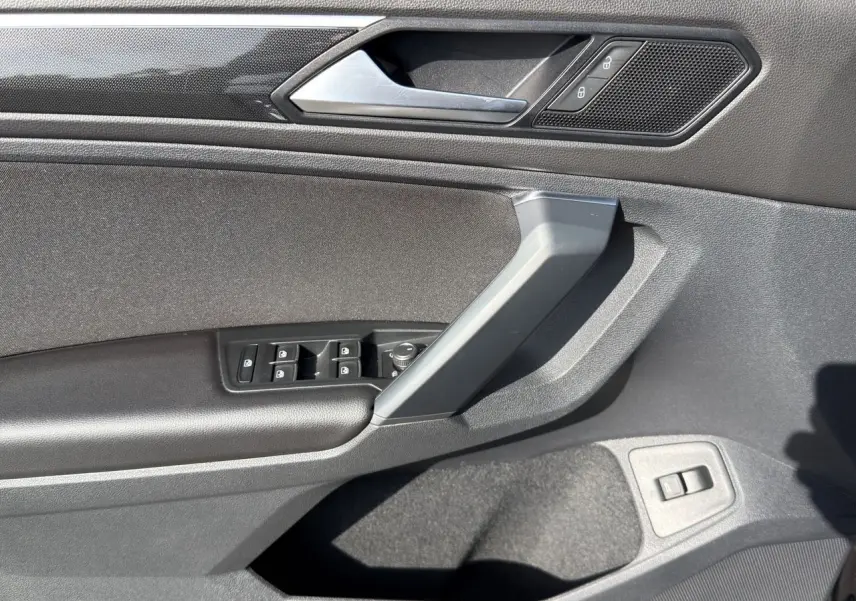 Vue rapprochée de la porte avant gauche noire intense du Volkswagen Tiguan 2022 avec commandes de vitres et verrouillage.