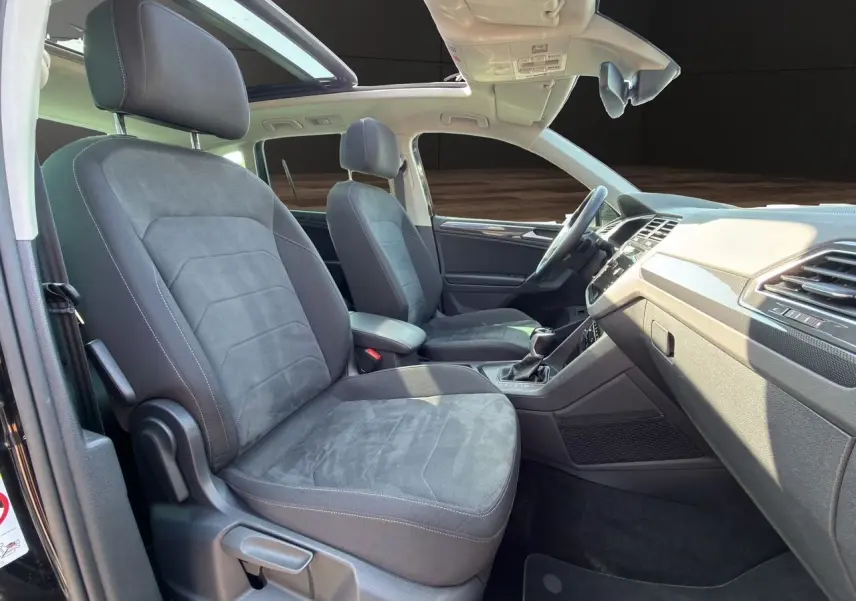 Vue intérieure côté gauche du Volkswagen Tiguan 2.0 TDI 150 DSG7 Elegance 2022 avec toit panoramique et sièges tissu noir.