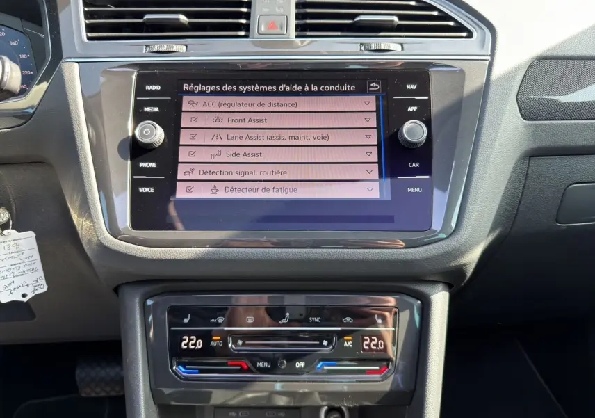 Vue rapprochée du tableau de bord noir du Volkswagen Tiguan 2022 avec écran tactile affichant les aides à la conduite.