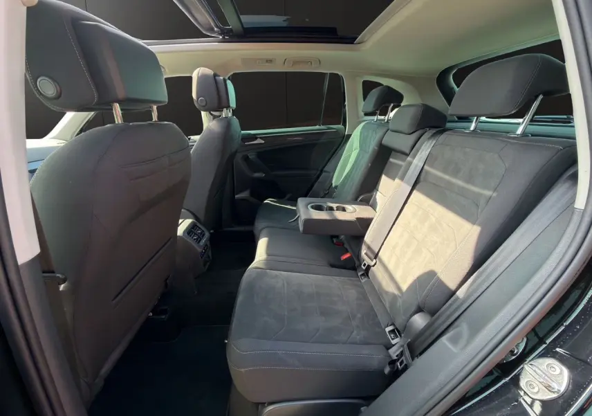 Vue intérieure côté droit des sièges arrière noirs du Volkswagen Tiguan 2.0 TDI avec accoudoir central et toit panoramique.