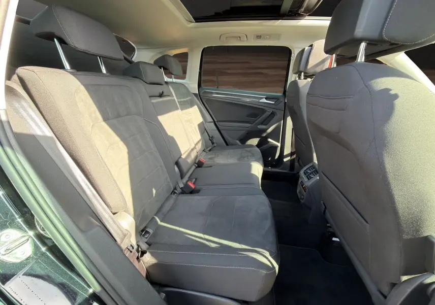Vue intérieure arrière du Volkswagen Tiguan noir intense 2022, montrant les sièges arrière en tissu noir et toit panoramique.