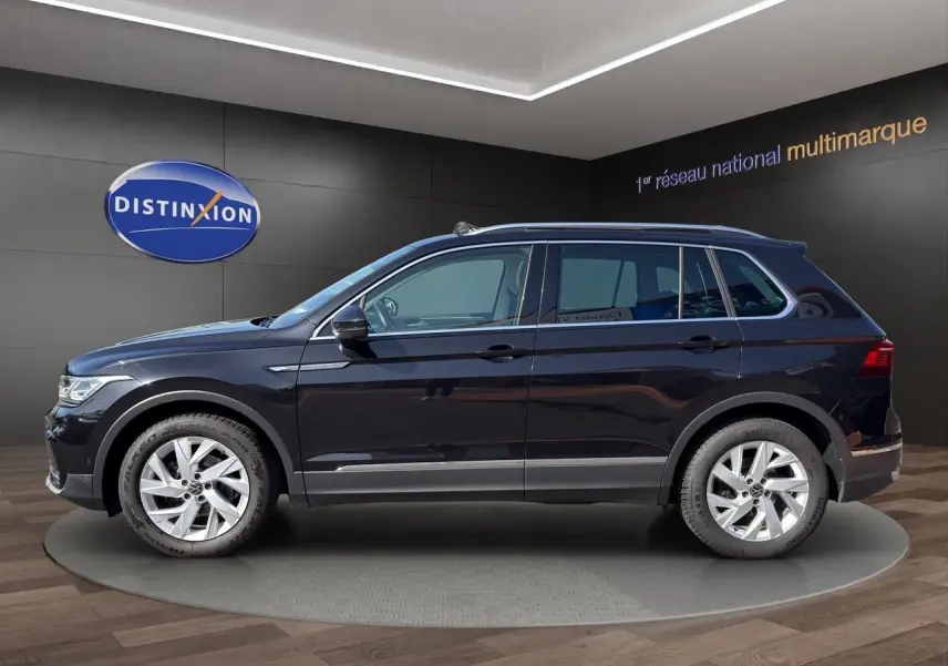 Vue de profil côté gauche d'un Volkswagen Tiguan noir intense avec jantes alu 18 pouces dans un showroom.