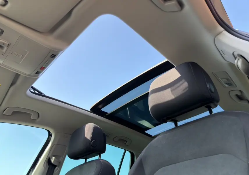 Vue intérieure du Volkswagen Tiguan 2022 noir intense, toit panoramique ouvert et sièges avant en tissu noir.