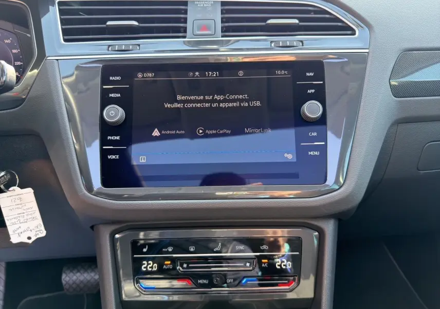 Vue intérieure du tableau de bord du Volkswagen Tiguan 2022, écran tactile et commandes climatisation en noir.