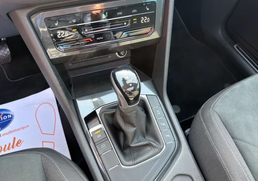 Vue rapprochée de la console centrale du Volkswagen Tiguan 2.0 TDI 150 DSG7 avec levier de vitesses et commandes climatisation digitale.