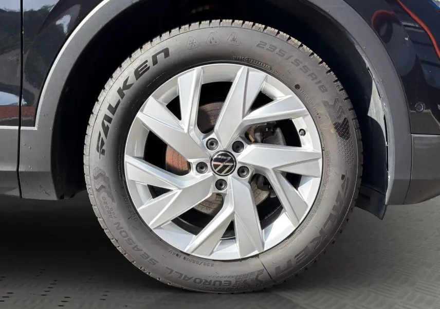 Gros plan sur la roue avant gauche d’un Volkswagen Tiguan noir intense avec jante alu 18 pouces et pneu Falken.