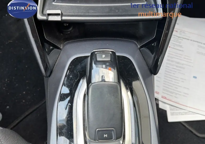 Le levier de vitesses automatique en gros plan au centre de la console d'une Peugeot 2008 rouge avec toit noir.