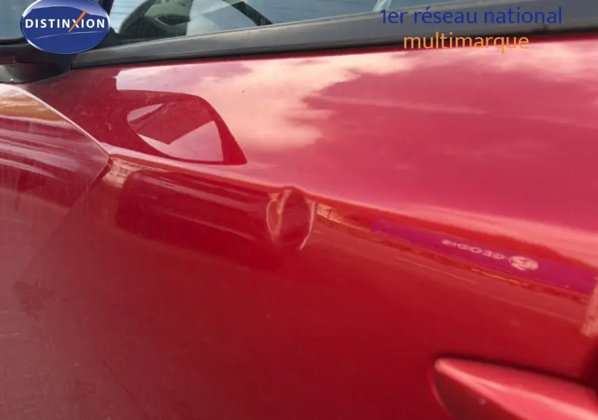 Gros plan sur la porte avant gauche rouge d’un Peugeot 2008 2020 avec toit noir, mettant en valeur la poignée et le rétroviseur.