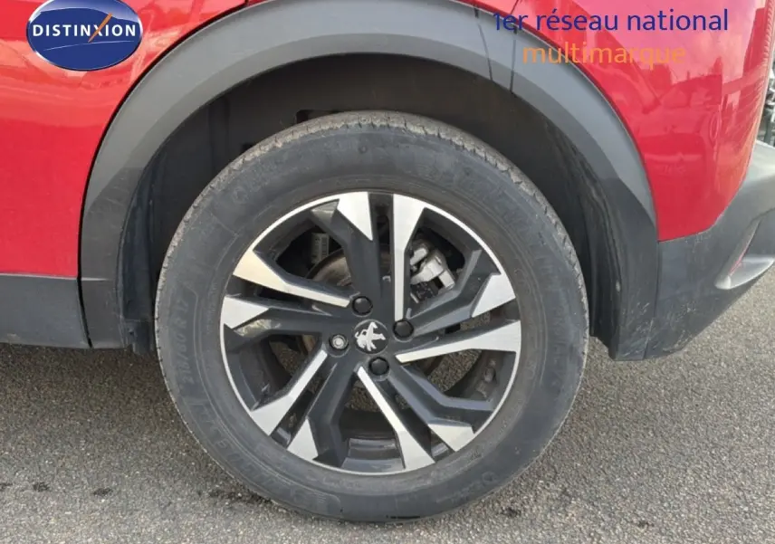 Gros plan sur la roue arrière droite d’un Peugeot 2008 rouge avec jante alliage bicolore et entourage noir.
