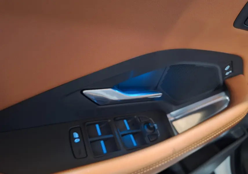 Détail de la portière côté gauche du Jaguar E-PACE blanc 2019 avec commandes de vitres et garniture cuir marron.