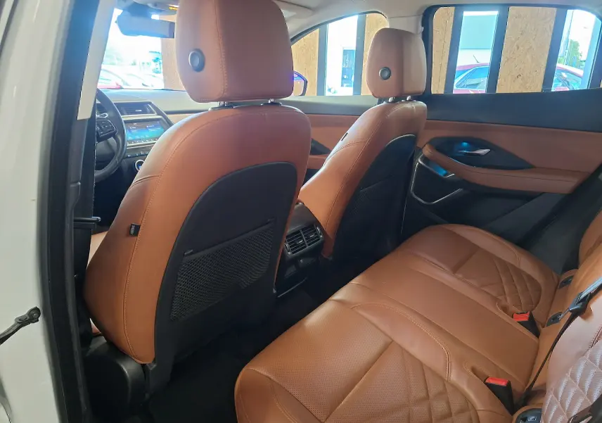 Vue intérieure arrière du Jaguar E-PACE blanc 2019 avec sièges en cuir marron et détails de porte assortis.