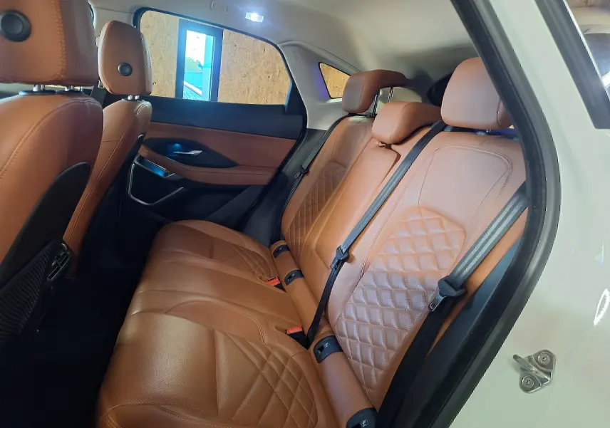 Vue latérale droite sur l'intérieur arrière du Jaguar E-PACE blanc avec sièges en cuir marron matelassé.
