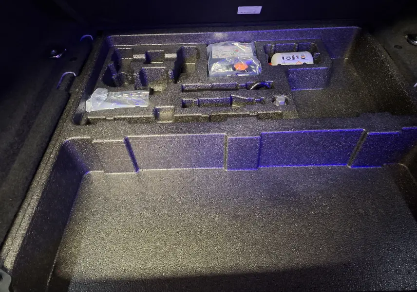 Rangement en mousse dans le coffre du Jaguar E-PACE blanc, compartiments pour outils et accessoires visibles.