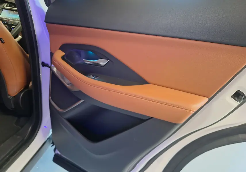 Gros plan sur la porte arrière gauche du Jaguar E-PACE blanc, avec garniture cuir marron et détails noirs.