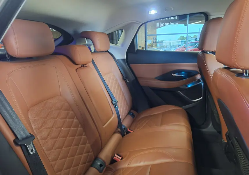 Vue intérieure arrière du Jaguar E-PACE 2019 montrant les sièges en cuir marron avec surpiqûres losanges et ceintures noires.