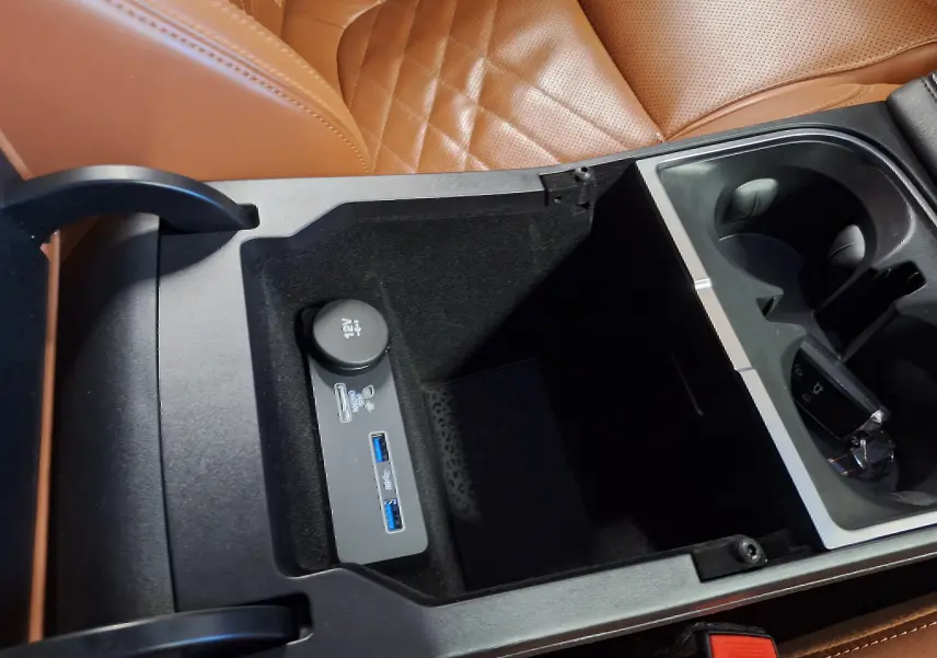 Intérieur Jaguar E-PACE 2019 montrant la console centrale ouverte avec ports USB et prise 12V, sièges cuir marron visibles