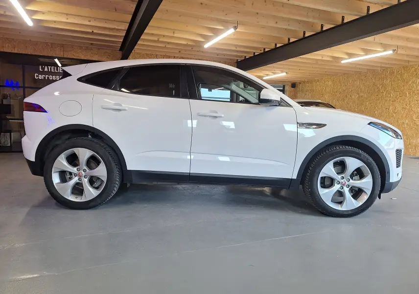 Profil côté droit d'un Jaguar E-PACE blanc 2019 dans un garage, soulignant ses lignes épurées et ses jantes alliage.