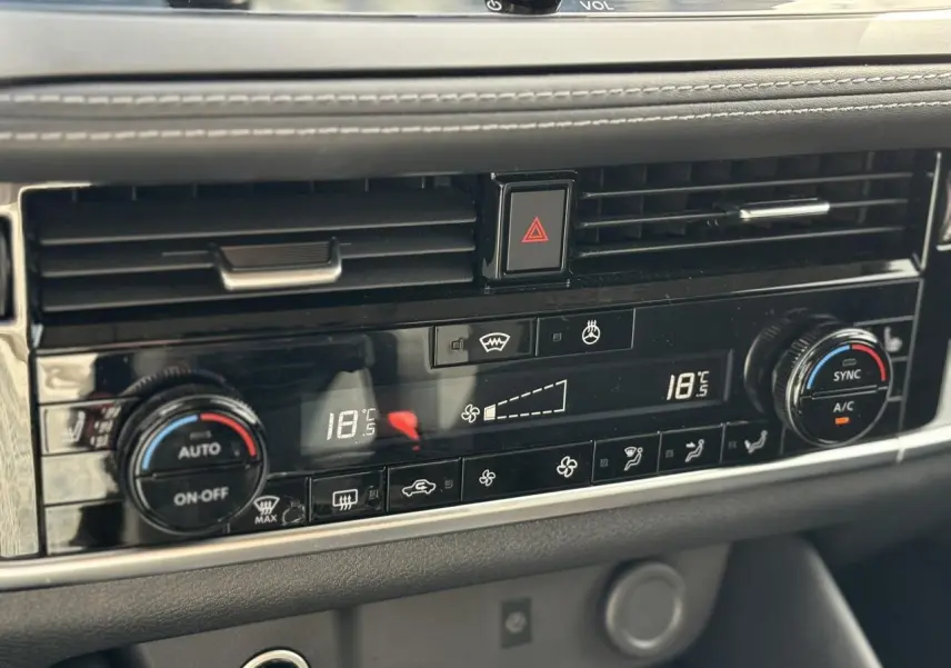 Détail de la console centrale noire du Nissan Qashqai 2025 avec climatisation automatique bi-zone et commandes tactiles.