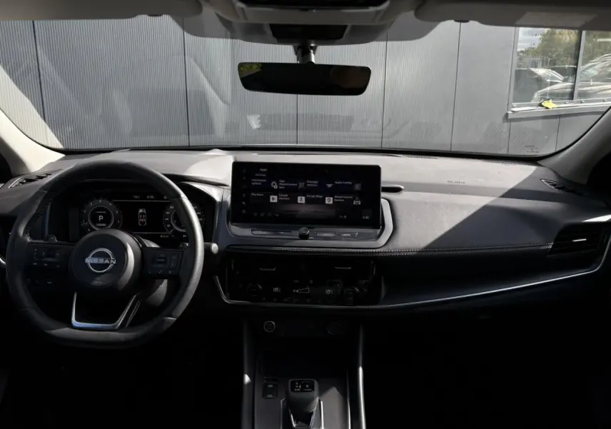 Vue intérieure du tableau de bord et volant cuir noir du Nissan Qashqai 2025 avec écran tactile central.