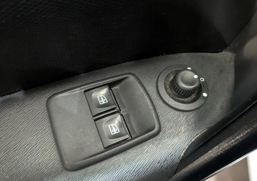 Gros plan sur les commandes électriques des vitres et le réglage des rétroviseurs côté conducteur du Renault Kangoo Express blanc.