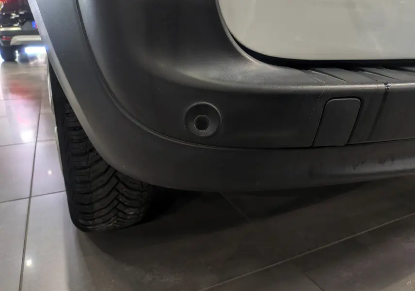 Gros plan sur le pare-chocs arrière droit noir du Renault Kangoo Express blanc minéral, avec capteur de recul visible.