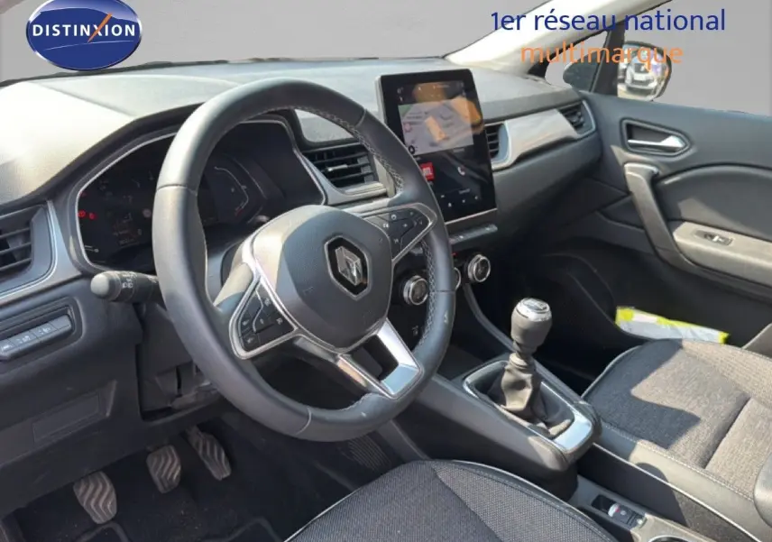 Vue intérieure côté conducteur du Renault Captur 2022 bleu marine fumé, avec volant multifonction et boîte manuelle.