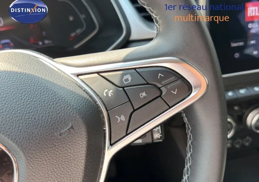 Gros plan sur les commandes au volant du Renault Captur 2022, version Intens, avec cuir noir et surpiqûres grises.