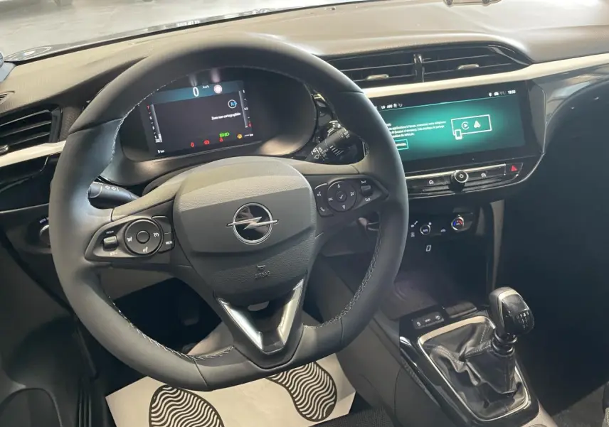 Vue intérieure centrée sur le volant cuir noir et la console avec levier de vitesse manuelle de l'Opel Corsa gris.