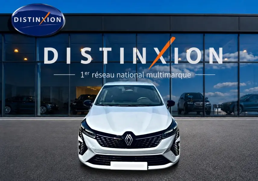 Vue frontale d'une Renault Clio V gris rafale garée devant une vitrine avec logo Distinxion.