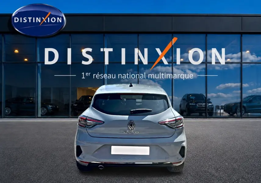 Vue arrière d'une Renault Clio V gris rafale garée devant une vitrine avec logo Distinxion.