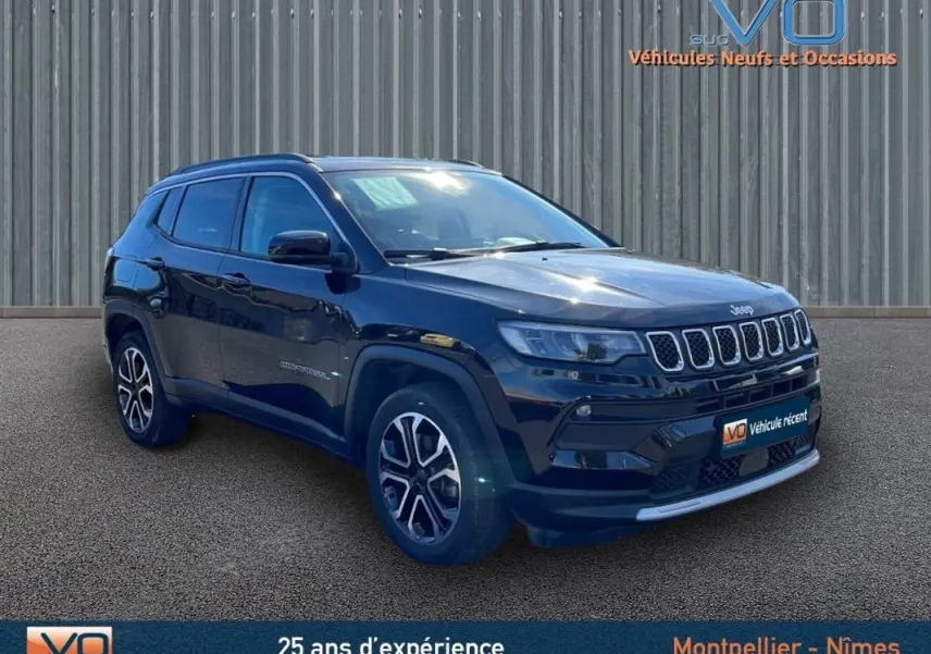 Jeep Compass noir vue 3/4 avant droit avec barres de toit et jantes 18 pouces sur fond industriel.