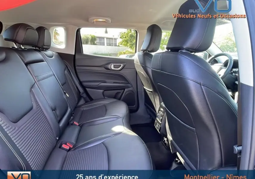 Vue intérieure arrière du Jeep Compass 2023 avec sièges cuir noirs et accoudoir central visible côté droit.