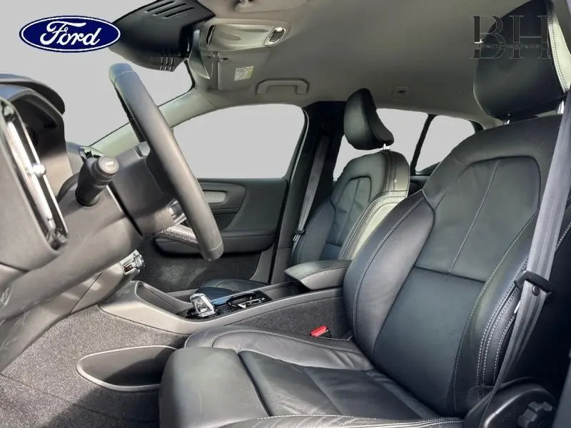 Vue intérieure côté conducteur du Volvo XC40 T4 Recharge 2021, sièges cuir anthracite avec accoudoir central et volant réglable.