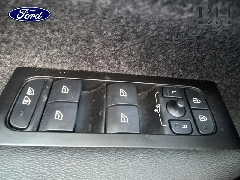 Panneau de commandes des vitres et rétroviseurs sur porte intérieure noire d'un Volvo XC40 Bleu Denim.