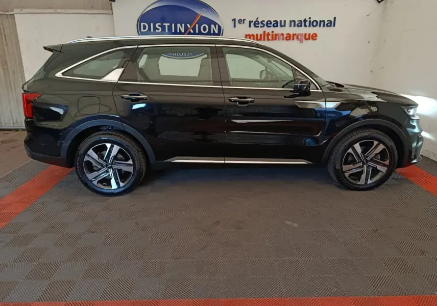 Vue latérale droite du KIA Sorento noir 2023 avec jantes alliage et rails de toit chromés en intérieur showroom.