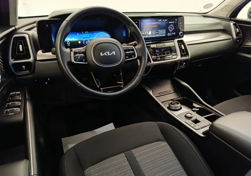 Vue intérieure avant du tableau de bord du Kia Sorento noir 2023 avec écran tactile et volant multifonctions en cuir.