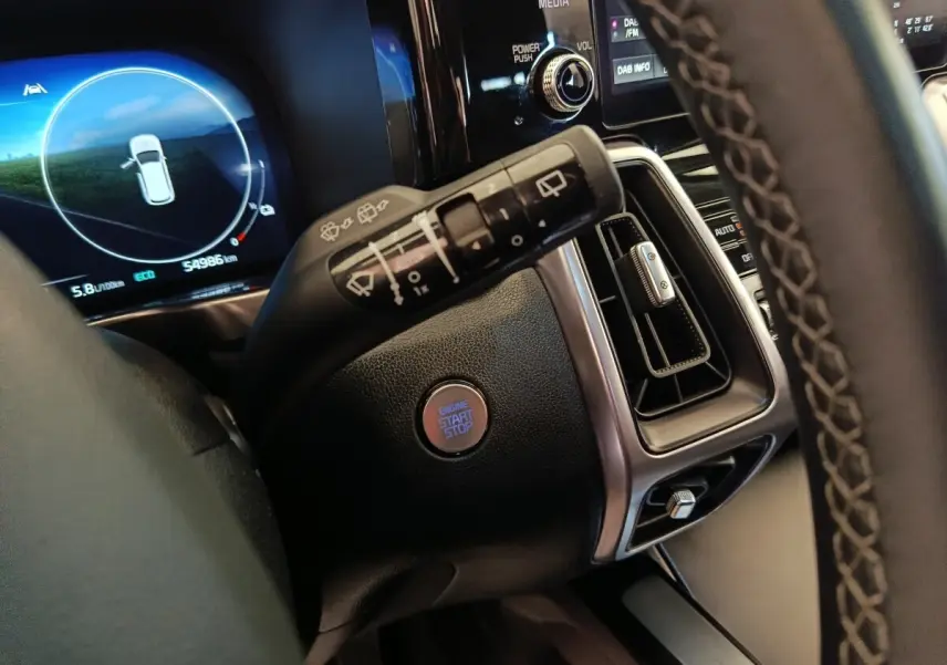 Gros plan intérieur sur la commande d’essuie-glace, bouton start/stop et tableau de bord numérique du Kia Sorento noir 2023.