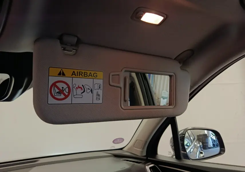 Vue intérieure côté conducteur du pare-soleil beige avec miroir et avertissement airbag du Kia Sorento noir 2023.