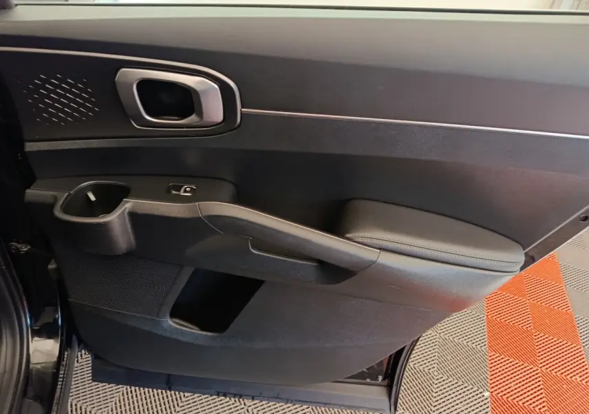 Vue intérieure du panneau de porte côté gauche noir du Kia Sorento 2023, avec accoudoir et poignée intégrée.