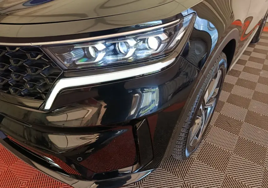Gros plan sur l’avant droit noir du KIA Sorento 2023, mettant en valeur le phare LED et la calandre distinctive.