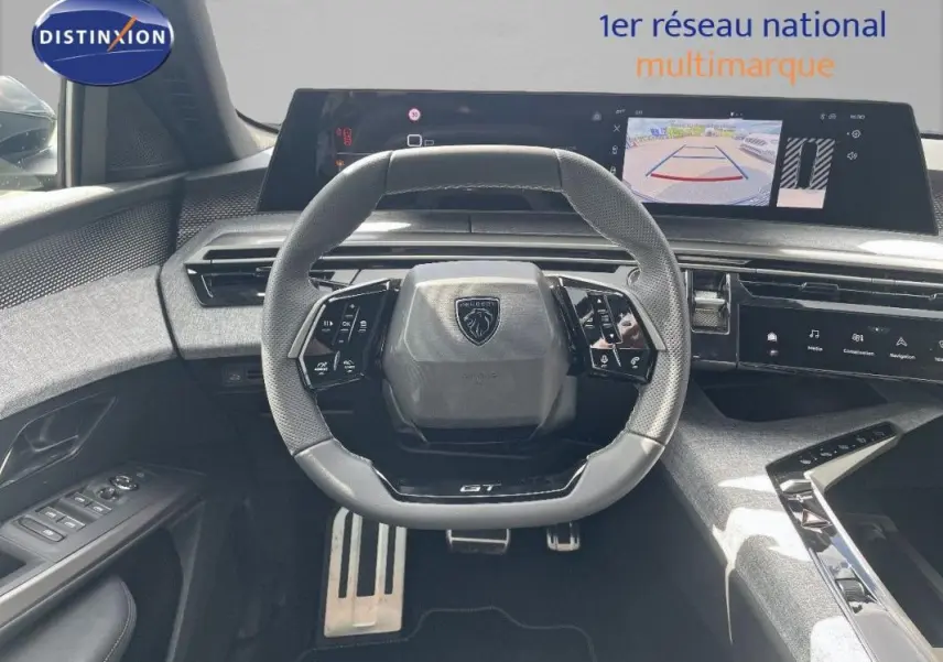 Vue intérieure centrée sur le volant cuir et le cockpit numérique du Peugeot 5008 noir, avec écran tactile et caméra de recul.