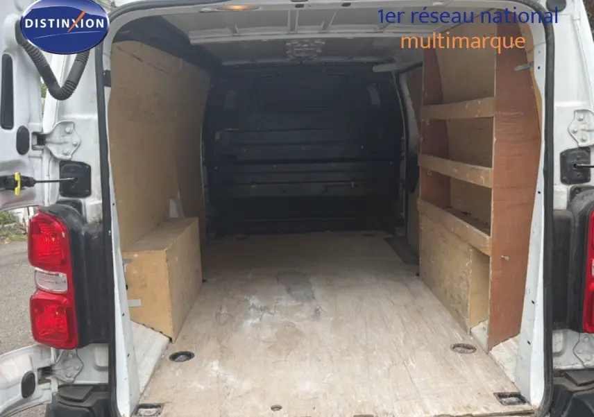 Vue arrière du Citroën Jumpy XL blanc 2017 avec portes ouvertes montrant l’espace de chargement et étagères en bois.