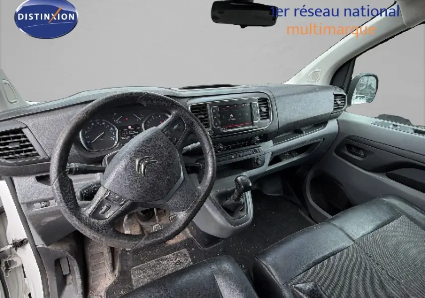 Vue intérieure côté conducteur du Citroën Jumpy blanc 2017, montrant le volant, tableau de bord et siège en cuir noir.