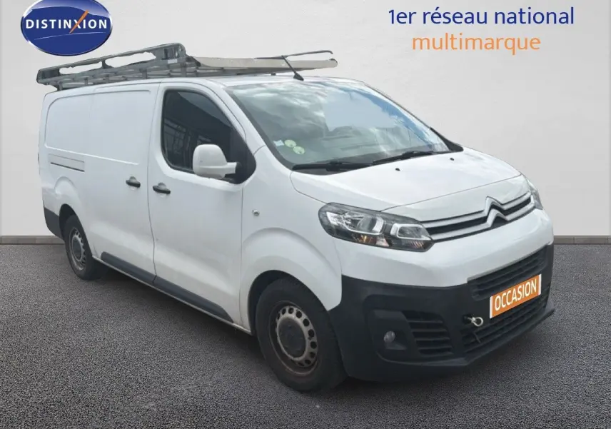 Vue 3/4 avant droit d’un Citroën Jumpy XL blanc avec galerie de toit et pare-chocs noir, en vente occasion.