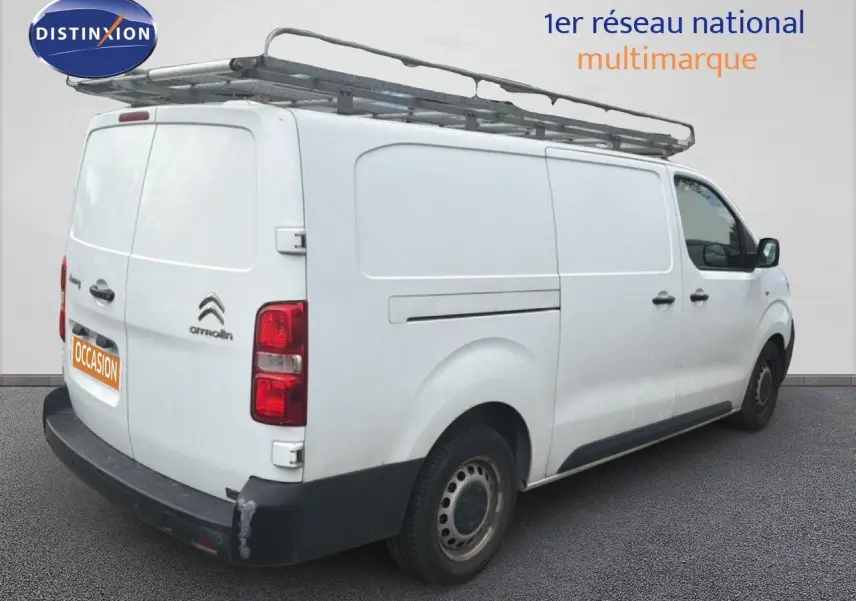Vue 3/4 arrière droite d’un Citroën Jumpy XL blanc avec galerie de toit et pare-chocs arrière noir.