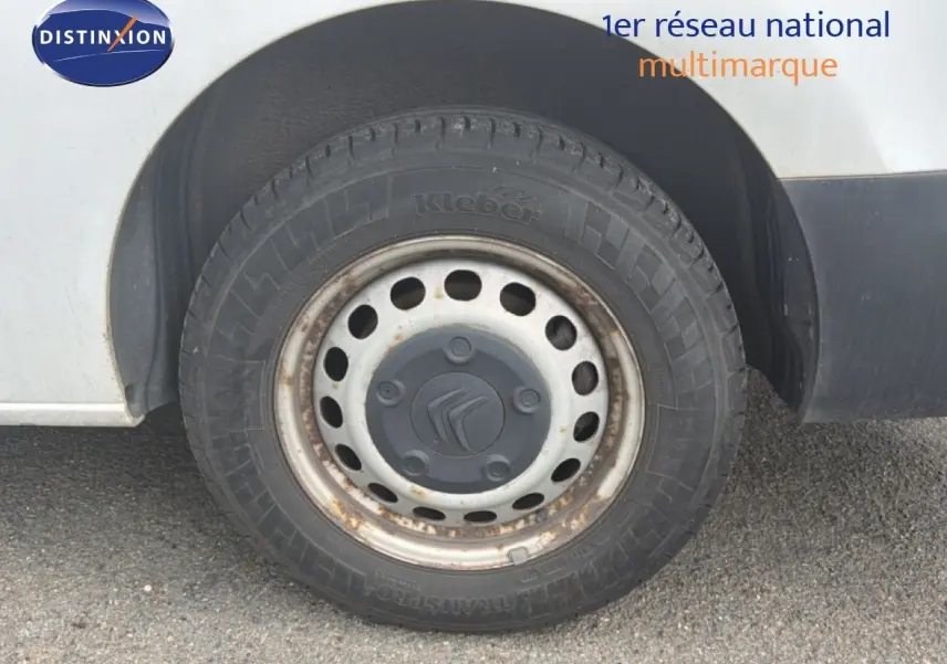 Gros plan sur la roue avant droite d’un Citroën Jumpy blanc, jante acier avec traces de rouille visibles.