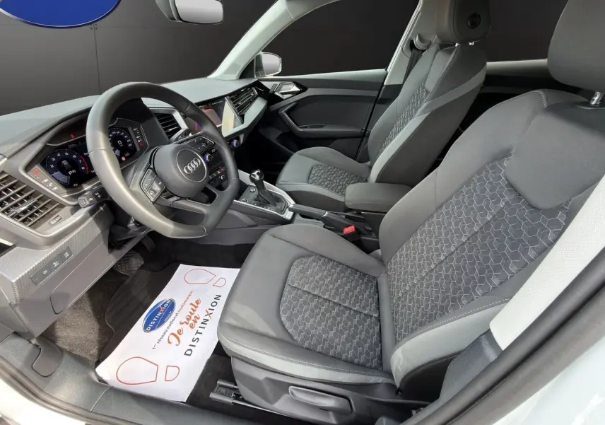 Vue intérieure côté conducteur de l'Audi A1 Sportback 2025 avec sièges tissu gris et tableau de bord moderne.